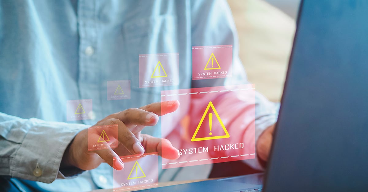 Healthcare executive looking at computer with "system hacked" warning.