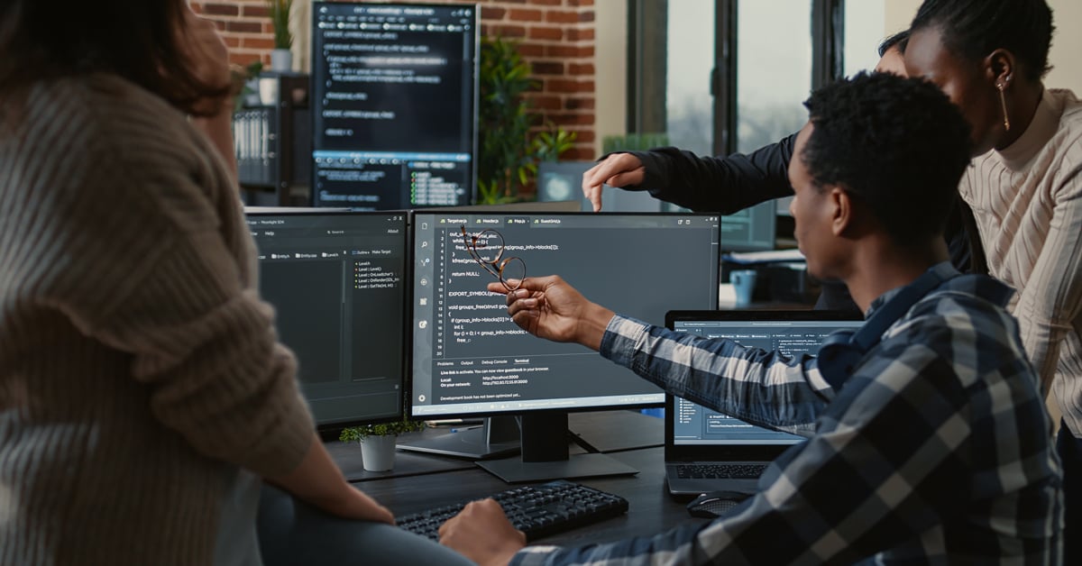 Group of IT pros looking at AI security on computers. 