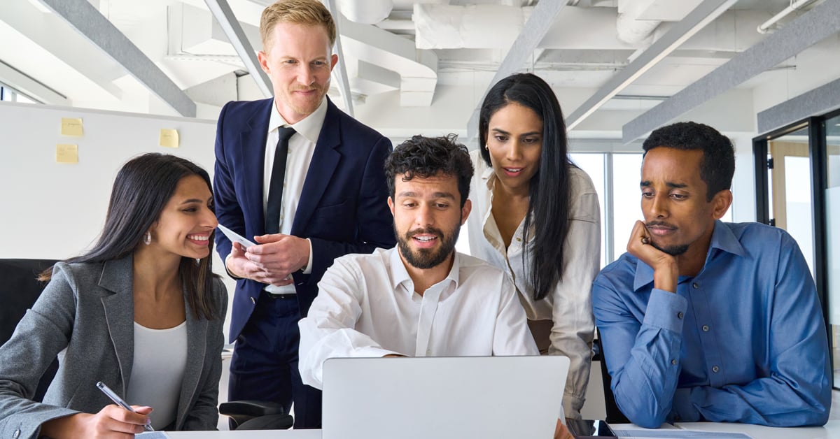 Professionals looking at a laptop in an office. 
