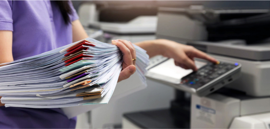 Person using printer, holding stack of papers