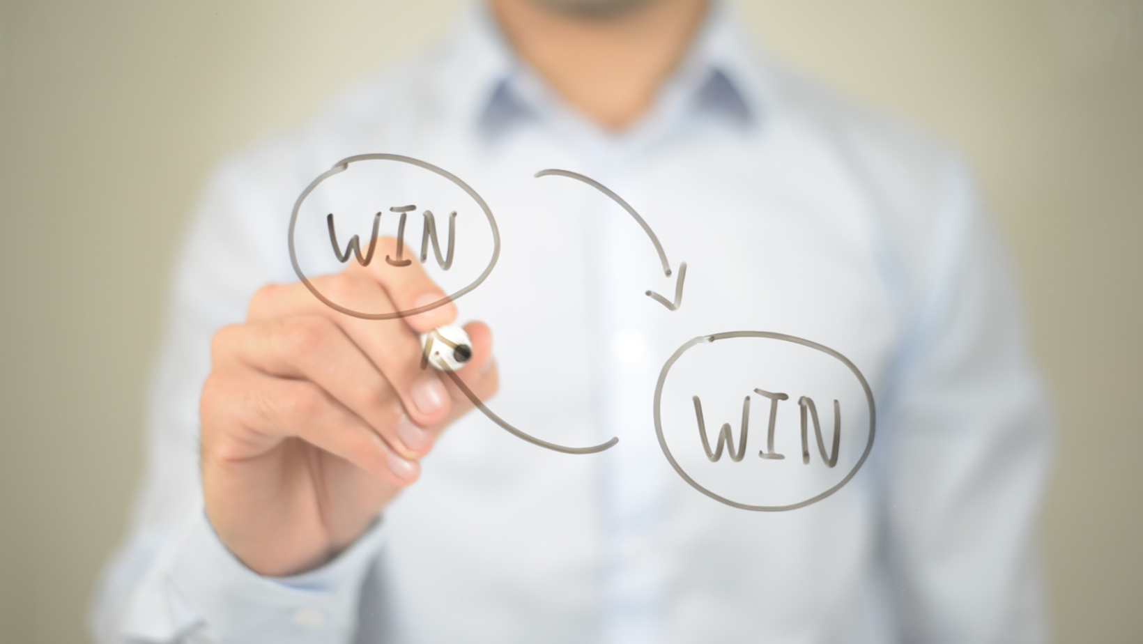 A businessman illustrates a win-win situation on a whiteboard.